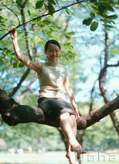 イラスト＆写真のストックフォトwaha（ワーハ）　人物、日本人、女性、20代、30代、公園、屋外、正面、全身、ポートレート、散歩、樹木の上、木登り、木の上に登る、葉、遊ぶ、森林浴、あそぶ、あそび、遊ぶ、遊び、座る　p2-0304a