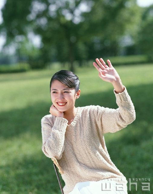 イラスト＆写真のストックフォトwaha（ワーハ）　人物、日本人、女性、20代、30代、屋外、正面、上半身、散歩、公園、広場、草原、休憩、頬杖をつく、椅子、見つめる、手を振る、呼ぶ、挨拶　p2-0653a