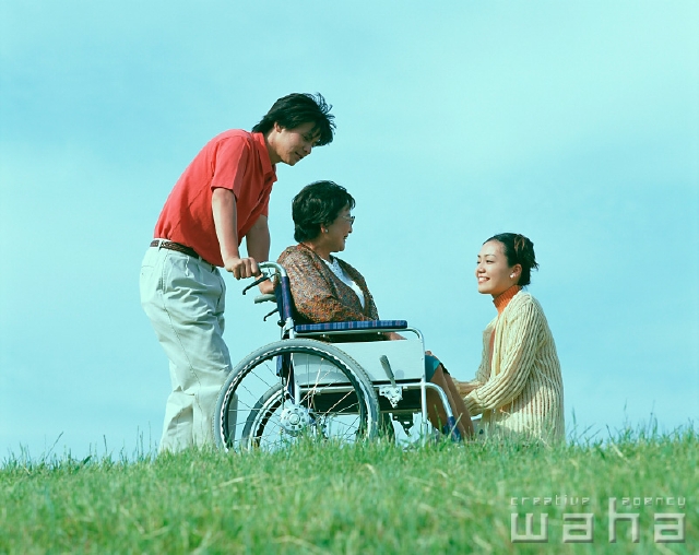 イラスト＆写真のストックフォトwaha（ワーハ）　人物、日本人、親子、屋外、横向き、横顔、全身、3人、シニア、休憩、散歩、土手、青空、草原、広場、車椅子、介護、福祉、看護、介抱、お世話をする、親孝行、仕事　p2-0978a