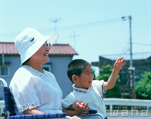 イラスト＆写真のストックフォトwaha（ワーハ）　人物、日本人、シニア、子供、屋外、横向き、横顔、上半身、2人、孫、散歩、笑う、青空、車椅子、介護、福祉、メガネ、手をつなぐ、手を振る、無邪気、看護、介抱、お世話をする、笑う、笑い、スマイル、仕事、子ども、こども　p2-0982a