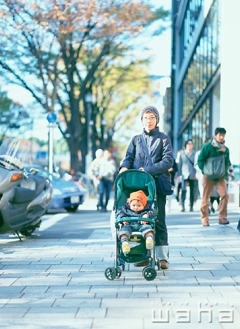 イラスト＆写真のストックフォトwaha（ワーハ）　人物、日本人、親子、屋外、正面、全身、ポートレート、2人、赤ちゃん、散歩、メガネ、ベビーカー、街角、ストリート、街と人、街並み、街並　p2-0985a