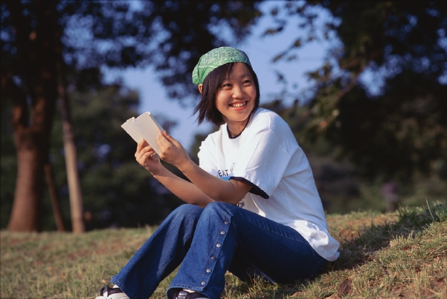 イラスト＆写真のストックフォトwaha（ワーハ）　人物、日本人、女性、若者、10代、20代、1人、屋外、公園、読書、座る、全身、笑顔、本、笑う、笑い、スマイル　p3-0826b