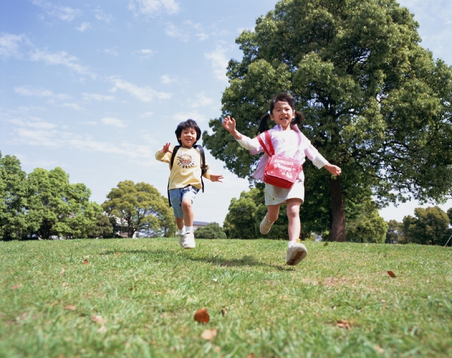 イラスト＆写真のストックフォトwaha（ワーハ）　人物、日本人、子供、小学生、男の子、女の子、2人、屋外、公園、草原、走る、全身、正面、笑顔、元気、ローアングル、笑う、笑い、スマイル　p3-0860bv