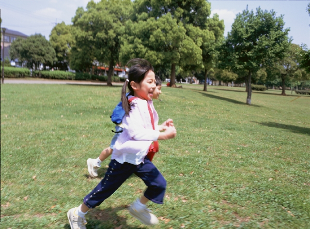 イラスト＆写真のストックフォトwaha（ワーハ）　人物、日本人、子供、小学生、女の子、1人、屋外、公園、草原、走る、全身、横向き、笑顔、元気、笑う、笑い、スマイル　p3-0861bv