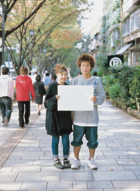 イラスト＆写真のストックフォトwaha（ワーハ）　人物、日本人、男性、女性、カップル、若者、10代、20代、2人、屋外、街、メッセージボード、正面、全身、街並み、街並　p3-1662b