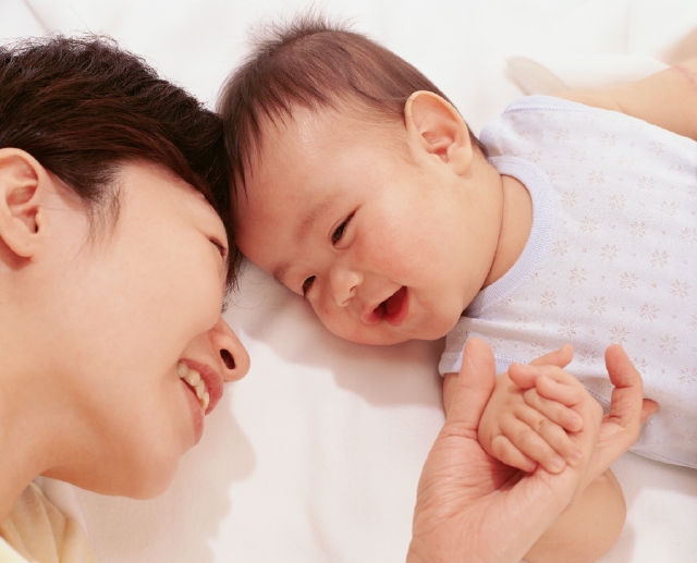 イラスト＆写真のストックフォトwaha（ワーハ）　人物、日本人、赤ちゃん、親子、愛情、白バック、2人、仰向け、横顔、上半身、顔、アップ、ハイアングル、白バック、育む、寝る、添い寝、ベビー服、手をつなぐ、あやす、信頼、幸福感、母性愛　p4-1100b