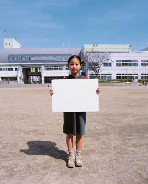 イラスト＆写真のストックフォトwaha（ワーハ）　人物、日本人、メッセージボード、小学生、学生、屋外、正面、上半身、ポートレート、校庭、校内、登校、登下校、通学　p4-1768b