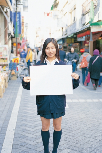 イラスト＆写真のストックフォトwaha（ワーハ）　人物、日本人、メッセージボード、高校生、学生、屋外、正面、上半身、ポートレート、女の子、通学路、町角、商店街、ストリート、寄り道、町並、町並み　p4-1780b