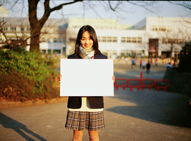 イラスト＆写真のストックフォトwaha（ワーハ）　人物、日本人、メッセージボード、高校生、学生、屋外、正面、上半身、ポートレート、女の子、校庭、マフラー　p4-1783b