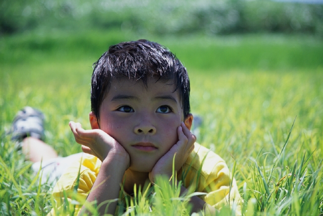 イラスト＆写真のストックフォトwaha（ワーハ）　人物、日本人、公園、夢、考える、子供、屋外、正面、アップ、逆光、頬杖をつく、寝転ぶ、見上げる、想像する、子ども、こども　p5-0035bv