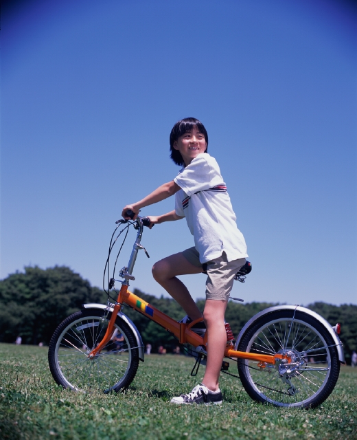 イラスト＆写真のストックフォトwaha（ワーハ）　人物、日本人、子供、自転車、公園、屋外、横向き、全身、青空、立ち止まる、ブレーキ、振り向く、ポロシャツ、スニーカー、片足を上げる、ハンドルを握る、ペダルを踏む、子ども、こども　p5-0095b