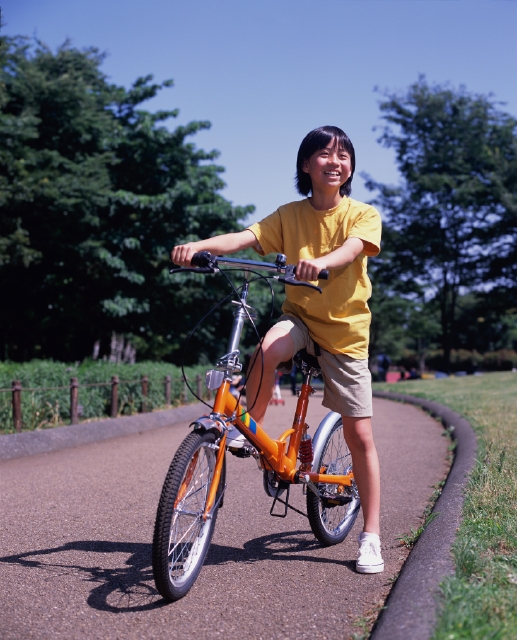 イラスト＆写真のストックフォトwaha（ワーハ）　人物、日本人、子供、自転車、公園、屋外、正面、全身、青空、森、林、緑、ロード、笑顔、立ち止まる、ブレーキ、眺める、ハンドルを握る、Tシャツ、スニーカー、楽しい、片足を上げる、ペダルを踏む、笑う、笑い、スマイル、子ども、こども　p5-0096bv