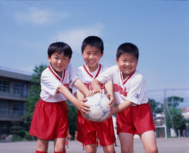 人物 日本人 スポーツ 子供 小学生 学生 屋外 正面 上半身 ポートレート 3人 グループ 仲間 友達 チームメイト サッカーボール ユニフォーム 笑顔 青空 グラウンド 校庭 チームワーク 持ち合う ポーズ 笑う 笑い スマイル 運動 子ども