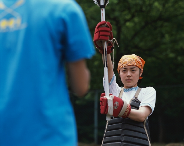 イラスト＆写真のストックフォトwaha（ワーハ）　人物、日本人、スポーツ、大学生、学生、屋外、正面、上半身、クロススティック、ラクロス、試合、ゲーム、グラウンド、校庭、見つめる、運動　p5-0713b