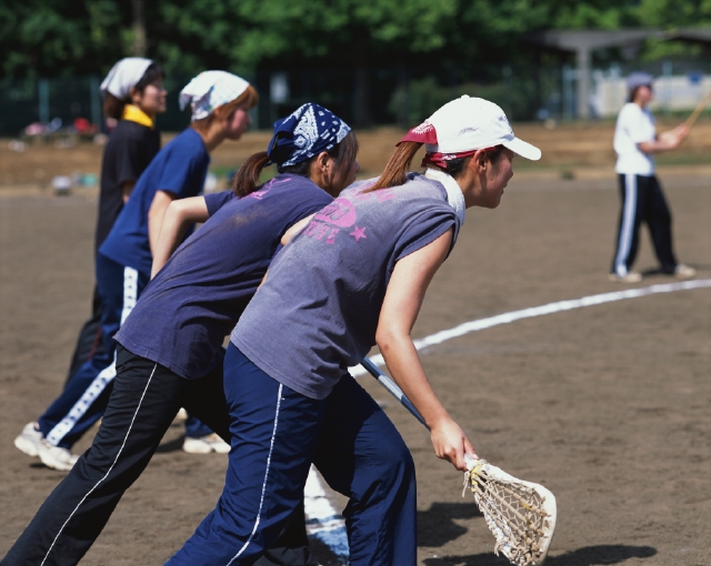 イラスト＆写真のストックフォトwaha（ワーハ）　人物、日本人、スポーツ、大学生、学生、屋外、横向き、横顔、背中、全身、グループ、仲間、クロススティック、ラクロス、試合、ゲーム、グラウンド、校庭、エネルギッシュ、運動　p5-0714b