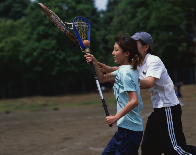 イラスト＆写真のストックフォトwaha（ワーハ）　人物、日本人、スポーツ、大学生、学生、屋外、横向き、横顔、上半身、2人、ラクロス、クロススティック、グラウンド、校庭、試合、ゲーム、戦う、運動　p5-0721bv