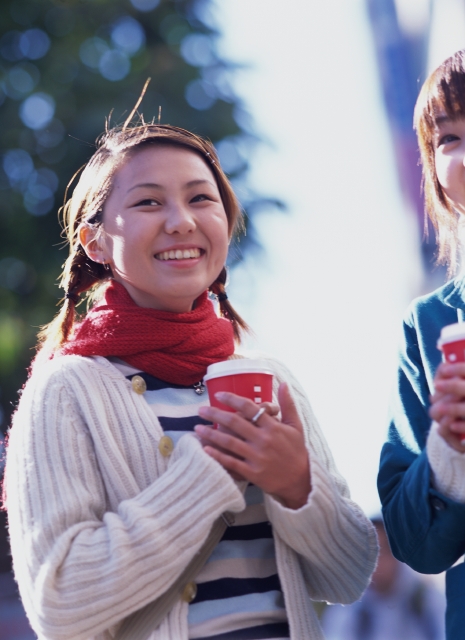 イラスト＆写真のストックフォトwaha（ワーハ）　人物、日本人、街、若者、笑顔、若者、屋外、正面、上半身、ポートレート、女の子、女性、楽しい、マフラー、飲む、ドリンク、コーヒー、温かい、笑う、笑い、スマイル、街並み、街並　p6-0531bv