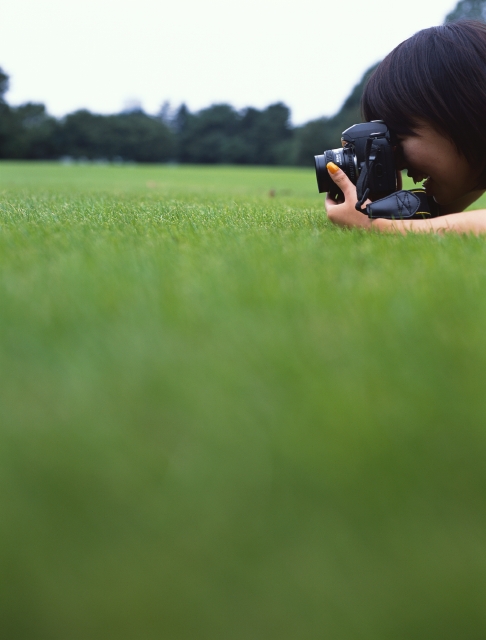 イラスト＆写真のストックフォトwaha（ワーハ）　人物、日本人、公園、若者、屋外、横向き、横顔、上半身、女の子、女性、カメラ、レンズ、写真、チーズ、広場、草原、覗く、趣味、地面、好奇心　p6-0951b