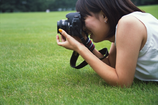 イラスト＆写真のストックフォトwaha（ワーハ）　人物、日本人、若者、公園、屋外、横向き、横顔、上半身、女の子、女性、カメラ、レンズ、写真、チーズ、広場、草原、覗く、趣味、好奇心　p6-0953b-data