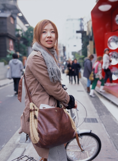 イラスト＆写真のストックフォトwaha（ワーハ）　人物、日本人、街、若者、自転車、屋外、横向き、正面、上半身、女の子、女性、振り向く、マフラー、コート、出発、運転、街並み、街並　p6-1587bv
