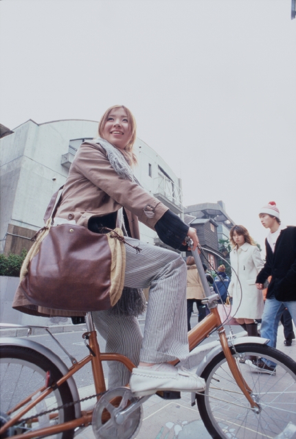 イラスト＆写真のストックフォトwaha（ワーハ）　人物、日本人、若者、自転車、街、屋外、横向き、正面、全身、女の子、女性、振り向く、マフラー、コート、出発、運転、空、街並み、街並　p6-1588b