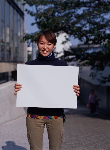 イラスト＆写真のストックフォトwaha（ワーハ）　人物、日本人、メッセージボード、若者、屋外、正面、上半身、ポートレート、女の子、女性、嬉しい、街角、街並み、街並　p6-1896b