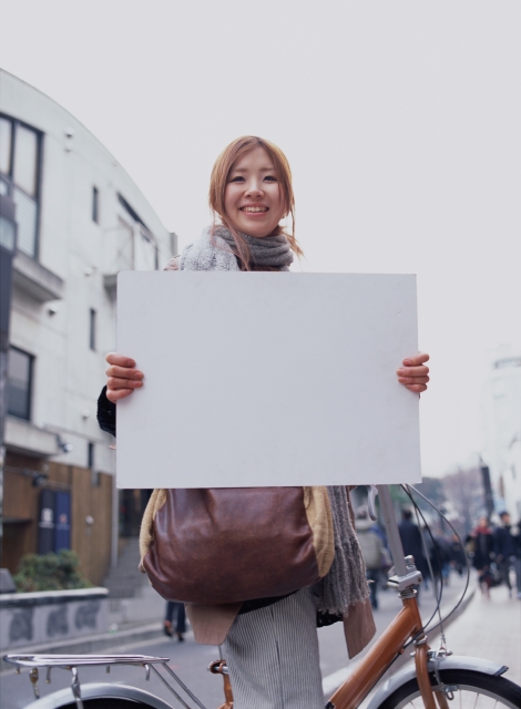 イラスト＆写真のストックフォトwaha（ワーハ）　人物、日本人、メッセージボード、若者、屋外、横向き、正面、上半身、ポートレート、女の子、女性、乗り物、自転車、マフラー、嬉しい、街角、ストリート、空、街並み、街並　p6-1946b