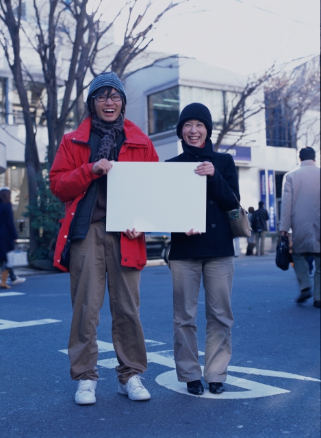 イラスト＆写真のストックフォトwaha（ワーハ）　人物、日本人、若者、メッセージボード、カップル、屋外、正面、全身、ポートレート、2人、男の子、男性、女の子、女性、メガネ、マフラー、コート、笑う、デート、街角、ストリート、笑う、笑い、スマイル、街並み、街並　p6-1947b