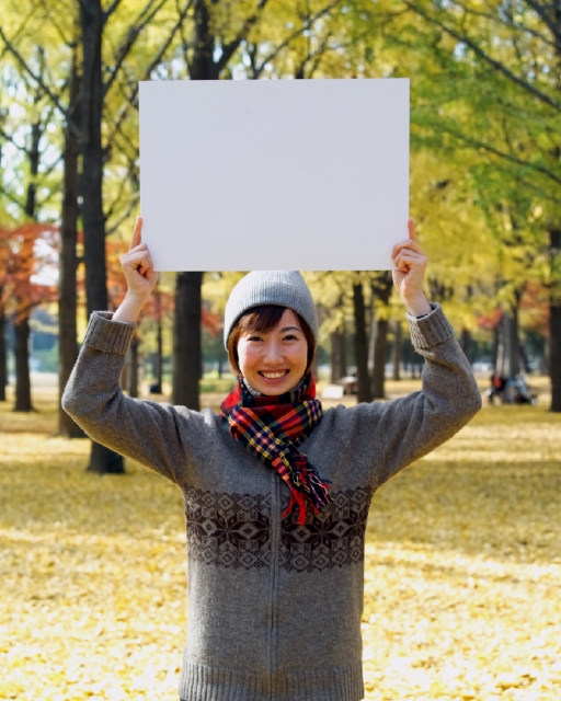 イラスト＆写真のストックフォトwaha（ワーハ）　人物、日本人、メッセージボード、公園、秋、屋外、正面、上半身、ポートレート、女性、20代、30代、散歩、笑う、林、枯れ葉、落ち葉、マフラー、笑う、笑い、スマイル、季節、四季　p8-0136b-data