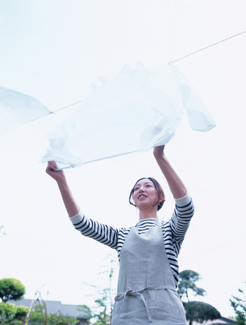 イラスト＆写真のストックフォトwaha（ワーハ）　人物、日本人、その他のスペース、女性、20代、30代、主婦、屋外、正面、上半身、ローングル、洗濯物、干す、シーツ、庭、なびく、はためく、空　p8-0288b