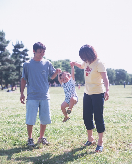 イラスト＆写真のストックフォトwaha（ワーハ）　人物、日本人、公園、家族、屋外、正面、全身、3人、父、母、子供、息子、愛情、親子、男の子、無邪気、幼い、赤ちゃん、散歩、広場、笑う、はしゃぐ、遊ぶ、手をつなぐ、ぶら下がる、幸福感、草原、あそぶ、あそび、遊ぶ、遊び、笑う　p8-1216bv