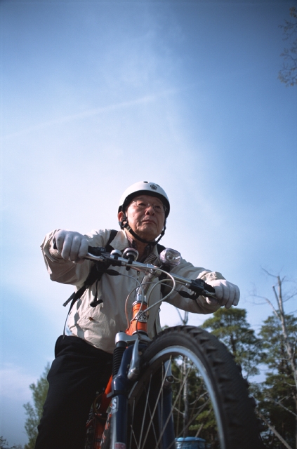 イラスト＆写真のストックフォトwaha（ワーハ）　人物、日本人、自転車、中高年、シニア、屋外、正面、上半身、ローアングル、男性、青空、ヘルメット、マウンテンバイク、メガネ、元気、エネルギッシュ　p8-1262b
