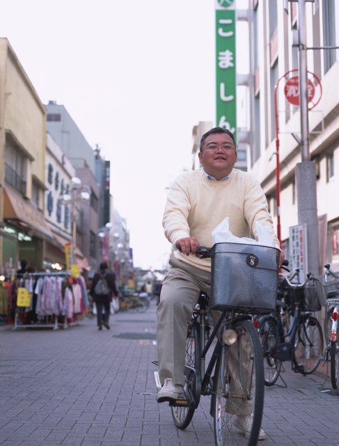 イラスト＆写真のストックフォトwaha（ワーハ）　人物、日本人、中高年、自転車、屋外、正面、全身、男性、ショッピング、おつかい、街角、ストリート、商店街、メガネ、レジ袋　p8-1291b