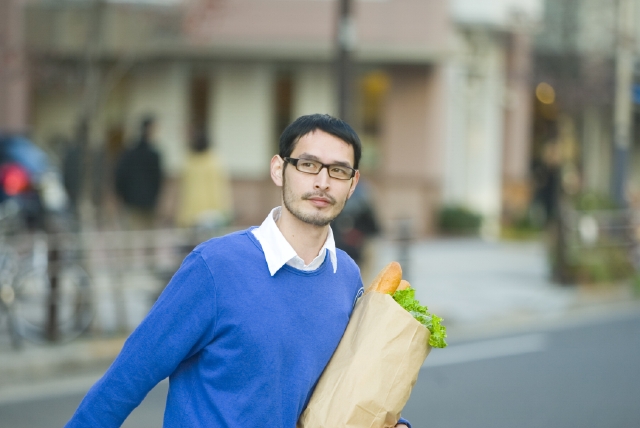 イラスト＆写真のストックフォトwaha（ワーハ）　人物、日本人、男性、20代、30代、1人、屋外、町、街、歩く、上半身、正面、持つ、メガネ、街、街並、街並み、モーニング、朝食、ランチ、昼食、フランスパン　w1-2069bv