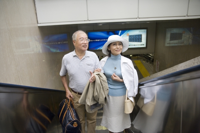 イラスト＆写真のストックフォトwaha（ワーハ）　人物、日本人、男性、女性、夫婦、シニア、2人、屋内、駅、正面、上半身、手をつなぐ　w1-3820bv