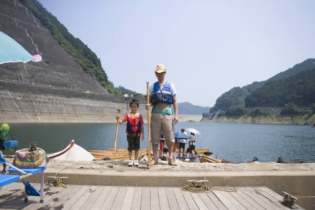 イラスト＆写真のストックフォトwaha（ワーハ）　人物、日本人、親子、父、子供、息子、男の子、2人、屋外、川、カヌー、レジャー、全身、正面、立つ、アウトドア、船、ふね、自然　w1-4021bv