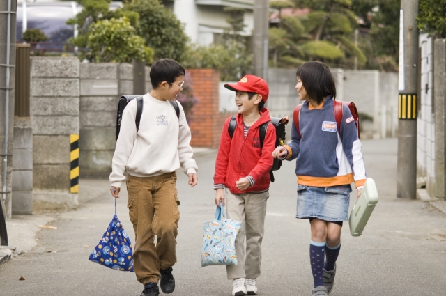 イラスト＆写真のストックフォトwaha（ワーハ）　人物、日本人、学生、小学生、男の子、女の子、グループ、友達、3人、屋外、町、住宅街、通学、登校、下校、歩く、会話、こども、子ども、子供、集合　w1-4718bv