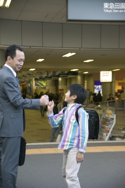 イラスト＆写真のストックフォトwaha（ワーハ）　人物、日本人、家族、親子、学生、小学生、男の子、息子、父、30代、40代、サラリーマン、2人、屋外、手をつなぐ、駅、朝、通学、登校、横向き、街、街並、街並み、こども、子ども、子供　w1-5082bv