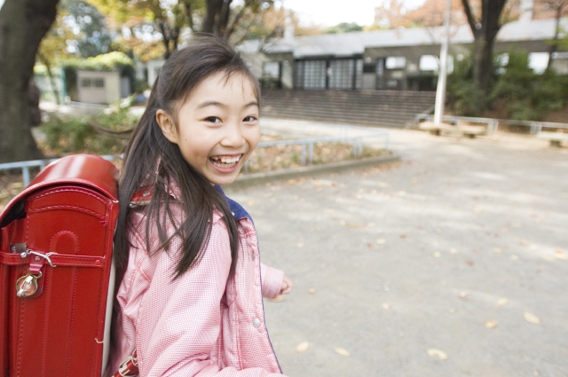 イラスト＆写真のストックフォトwaha（ワーハ）　人物、日本人、学生、小学生、女の子、1人、屋外、公園、学校、走る、振り向く、通学、登校、下校、上半身、笑顔、こども、子ども、子供、笑顔、笑い、笑う、スマイル　w1-5356bv