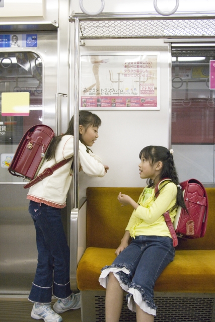 イラスト＆写真のストックフォトwaha（ワーハ）　人物、日本人、学生、小学生、女の子、友達、2人、屋内、車内、乗り物、電車、通学、登校、下校、会話、こども、子ども、子供、車内　w1-5421bv