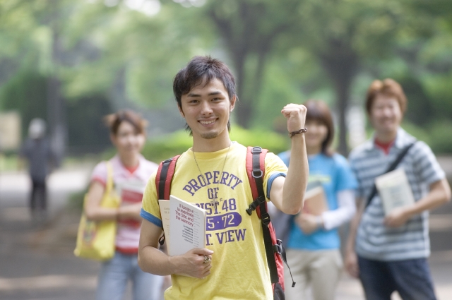 イラスト＆写真のストックフォトwaha（ワーハ）　人物、日本人、男性、若者、学生、大学生、友達、仲間、10代、20代、4人、屋外、公園、ガッツポーズ、持つ、本、上半身、正面　w1-9191b