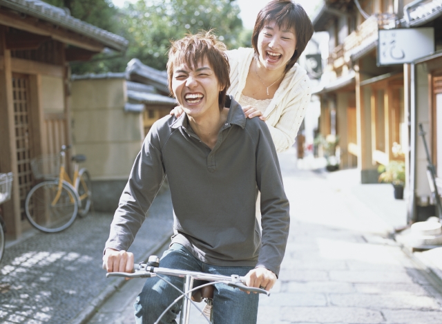 イラスト＆写真のストックフォトwaha（ワーハ）　人物、日本人、男性、女性、若者、カップル、20代、2人、屋外、町、町並み、旅行、観光、乗り物、自転車、笑顔、上半身、正面、町、町並、町並み、笑顔、笑い、笑う、スマイル　w1-9438bv