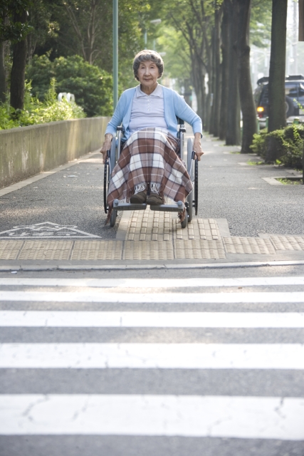 イラスト＆写真のストックフォトwaha（ワーハ）　人物、日本人、女性、シニア、1人、屋外、街、町、横断歩道、乗り物、車椅子、全身、正面、福祉、ポートレート、仕事　w2-1604bv
