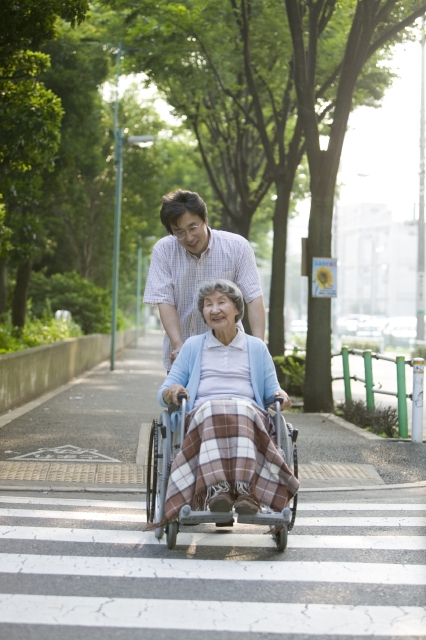 イラスト＆写真のストックフォトwaha（ワーハ）　人物、日本人、女性、家族、父、祖母、シニア、2人、屋外、街、町、横断歩道、乗り物、車椅子、全身、正面、福祉、仕事　w2-1609bv