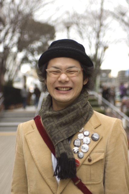 イラスト＆写真のストックフォトwaha（ワーハ）　人物、日本人、男性、若者、10代、20代、1人、屋外、街、笑顔、帽子、メガネ、マフラー、上半身、正面、ポートレート、街、街並み、街並、笑顔、笑い、笑う、スマイル　w2-1842bv