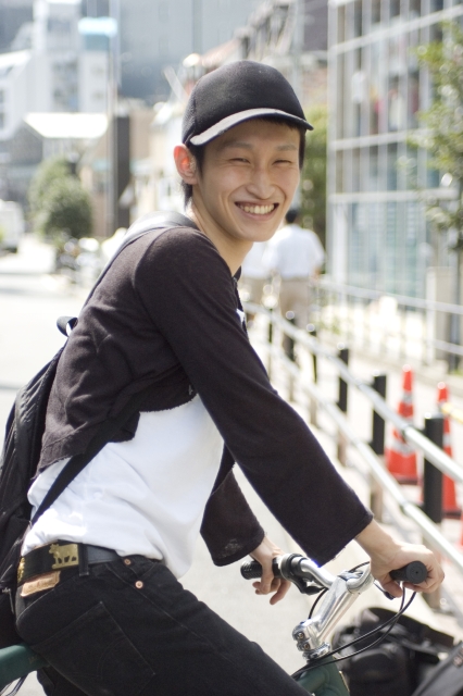 イラスト＆写真のストックフォトwaha（ワーハ）　人物、日本人、男性、若者、20代、1人、屋外、街、乗り物、帽子、自転車、笑顔、上半身、ポートレート、街、街並み、街並、笑顔、笑い、笑う、スマイル　w2-2076b