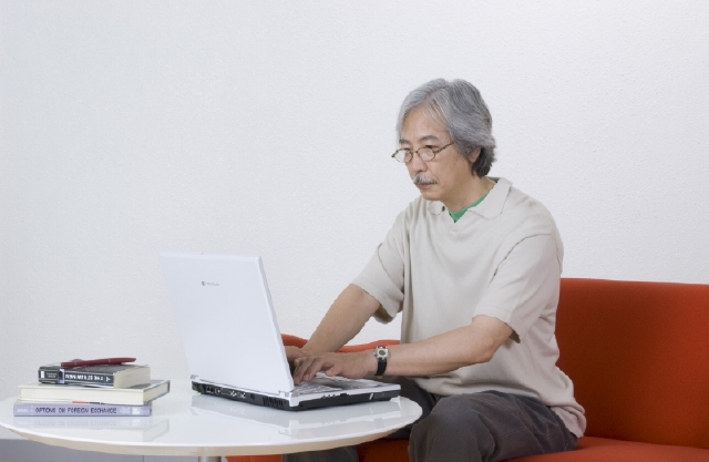 イラスト＆写真のストックフォトwaha（ワーハ）　人物、日本人、男性、シニア、中高年、1人、屋内、住宅、リビング、ソファ、パソコン　w2-4384b
