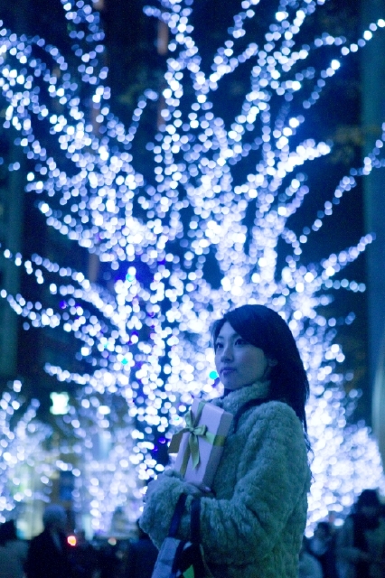 イラスト＆写真のストックフォトwaha（ワーハ）　人物、日本人、女性、20代、1人、屋外、冬、クリスマス、夜、イルミネーション、プレゼント、上半身、ギフト、贈り物、夜景、季節、四季、行事　w2-5045b
