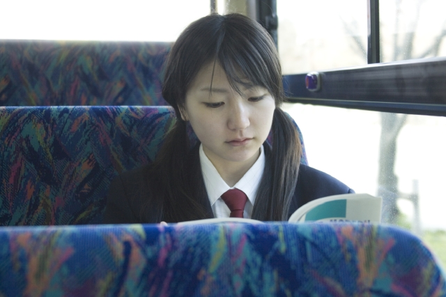 イラスト＆写真のストックフォトwaha（ワーハ）　人物、日本人、女性、学生、高校生、女子高生、10代、1人、屋内、乗り物、バス、車内、教科書、車内、車内　w2-5604b