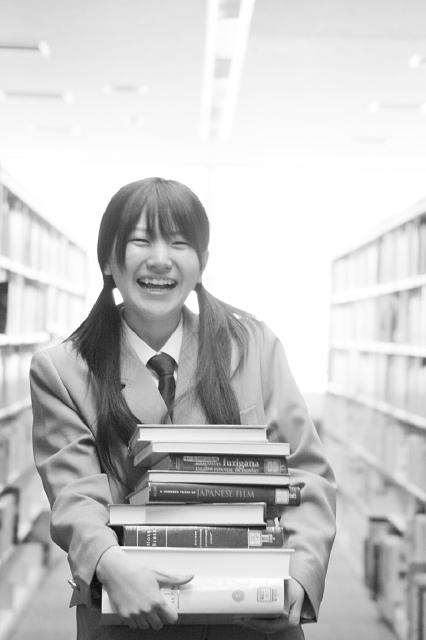イラスト＆写真のストックフォトwaha（ワーハ）　人物、日本人、女性、学生、高校生、女子高生、10代、1人、屋内、図書館、本、持つ、笑顔、上半身、正面、笑顔、笑い、笑う、スマイル　w2-6799b